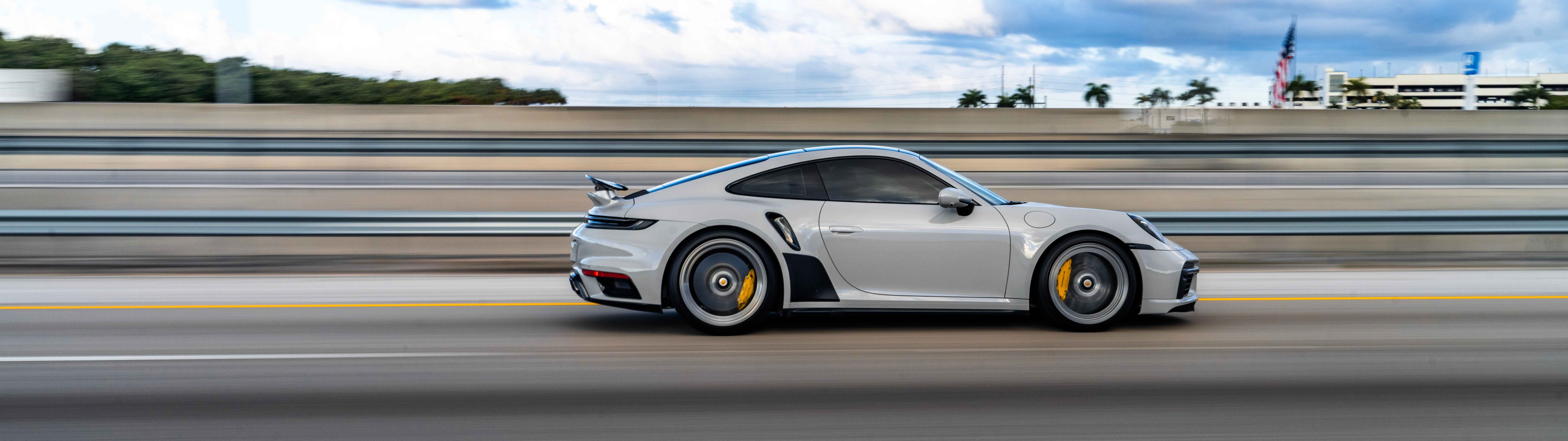 Zbliżenie ukazujące luksusowy sportowy samochód marki Porsche, charakteryzujący się eleganckim designem i metalicznym wykończeniem.